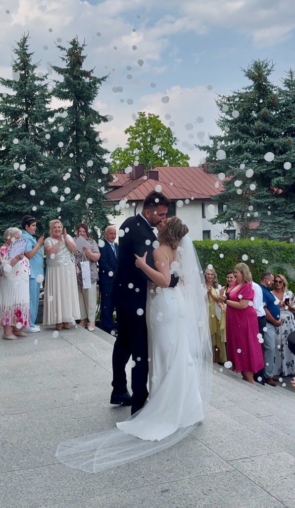 Para Młoda wśród baniek mydlanych — pocałunek przed gośćmi