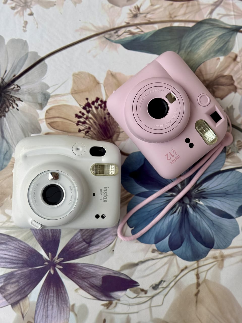 Aparaty Instax Mini — różowy i biały na tle kwiatowym