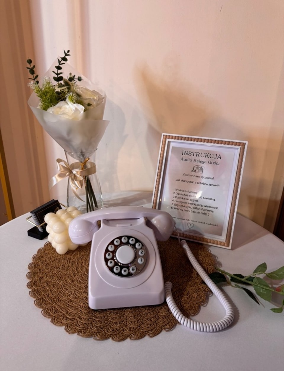 Audio księga gości — telefon życzeń z tabliczką instrukcji, kwiatami i dekoracjami na stole